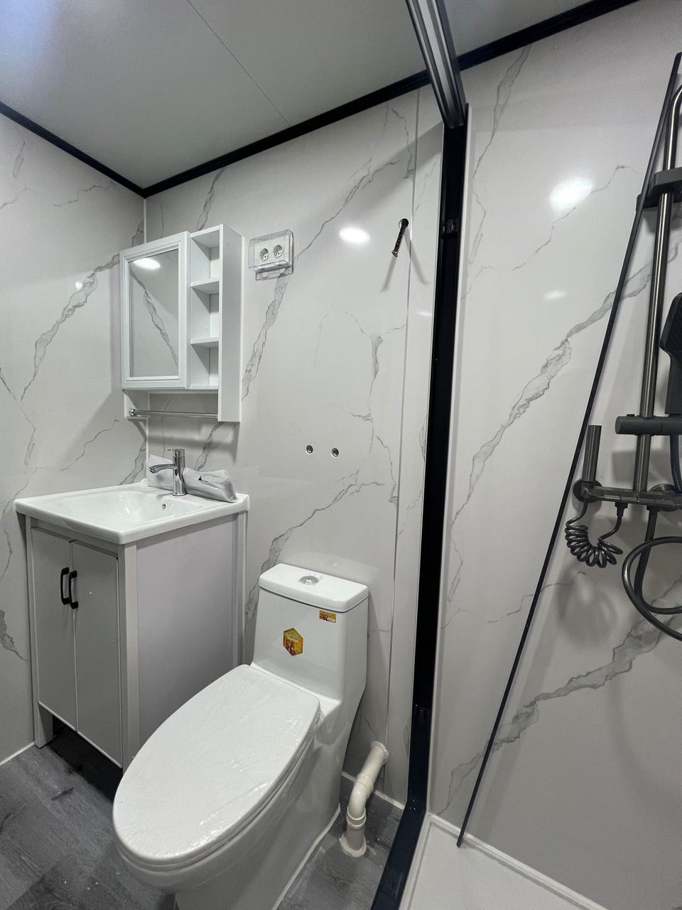 Баня с мраморна облицовка, огледален шкаф и душ